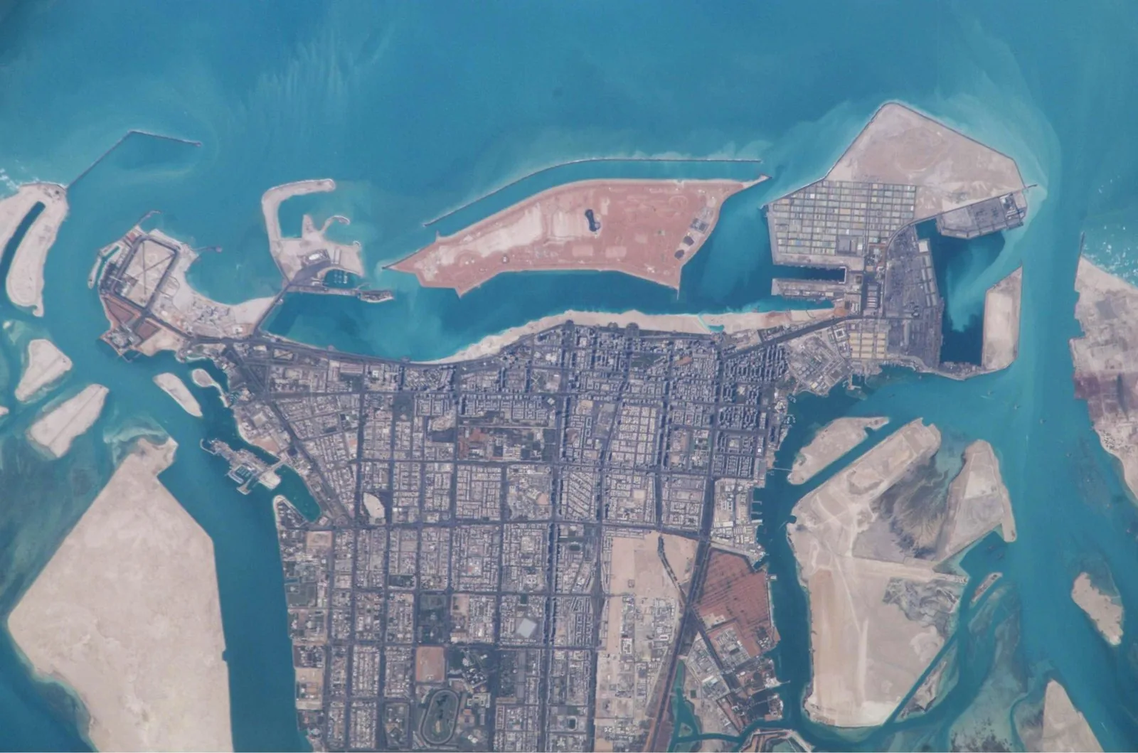 Satellite photograph of Abu Dhabi island from the ISS (2003), showing the island's planned grid-iron urban structure and the geometry that the Plan Abu Dhabi 2030 framework was designed to extend. The