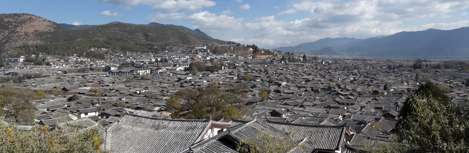 Elevated panorama over the tiled rooftops of Lijiang Old Town (Naxi).